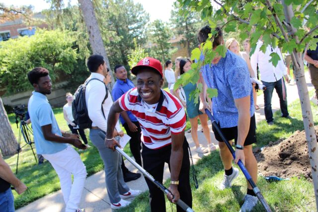 A Clarke student shovels dirt to help plant a tree.