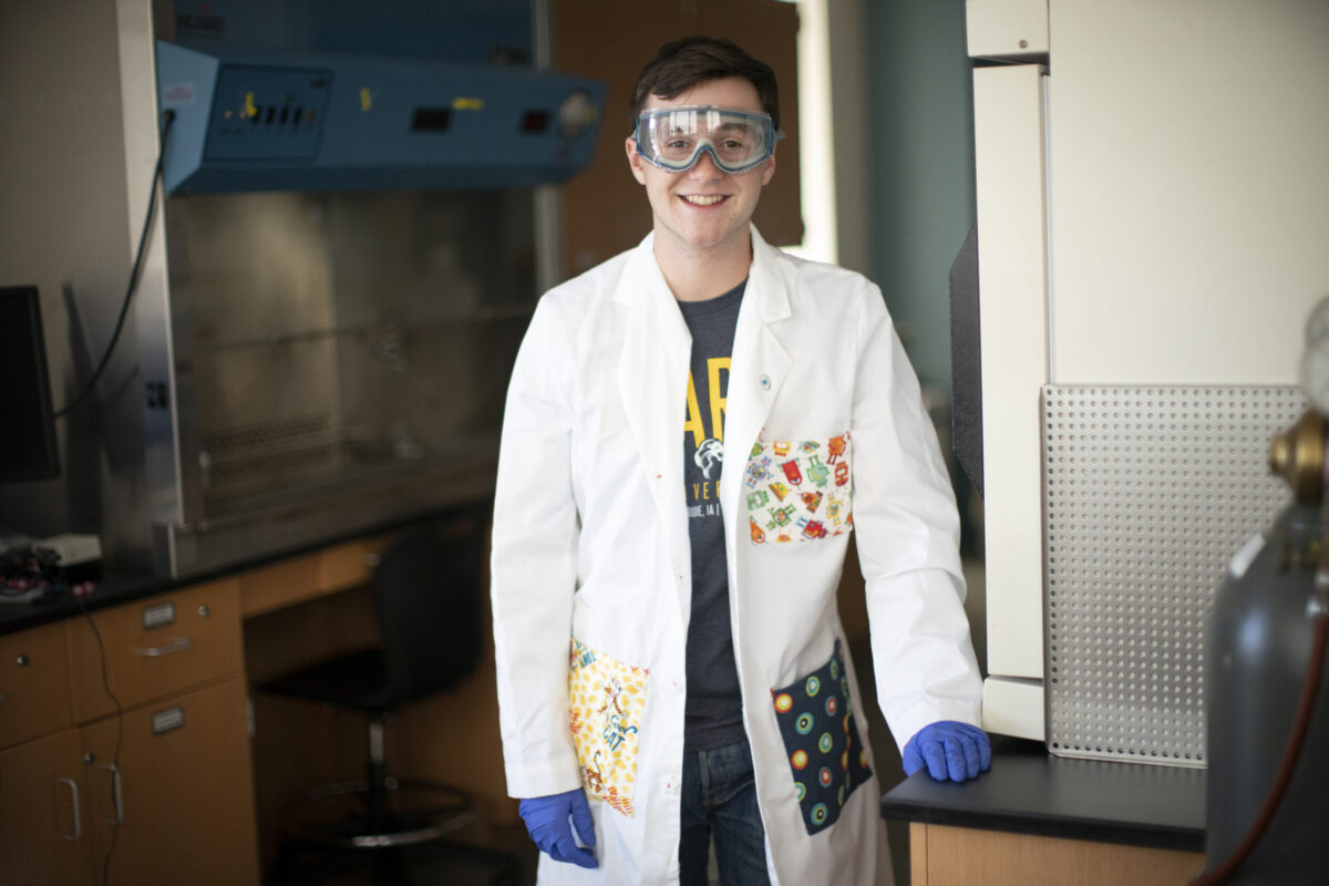 A young gentleman in a lab coat in a science classroom. - Full Size
