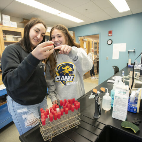 Two young women looking at a test tube in a science classroom.