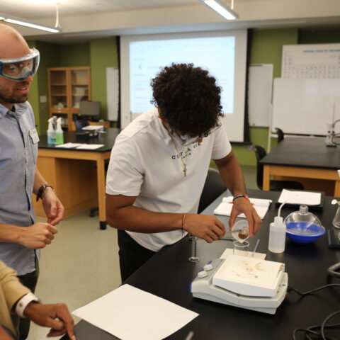 A male teacher watching a student measure ingredients.