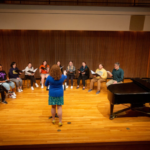 A female professor leading a full choir.
