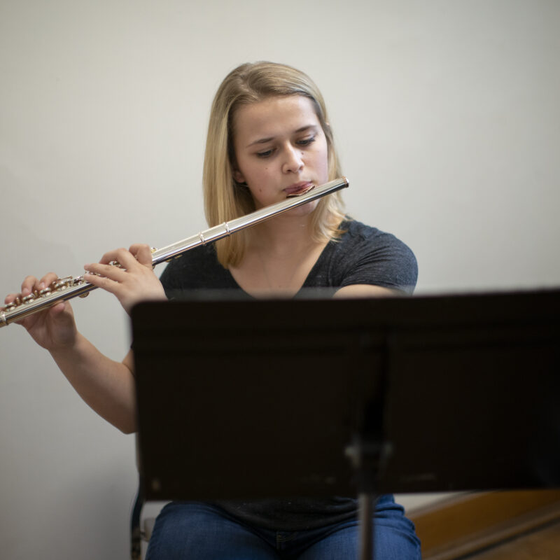 A young women playing a flute.