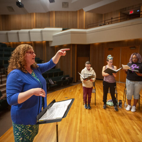 A female music professor leading a choir practice.