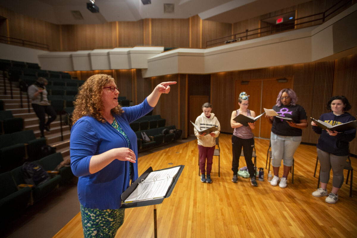 A female music professor leading a choir practice. - Full Size
