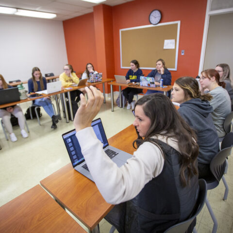 A student raising their hand in a classroom.