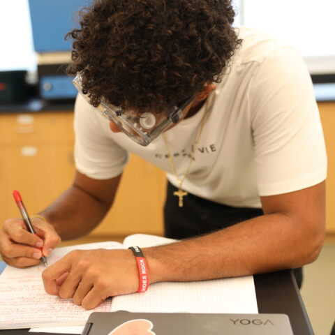 A male college student taking notes of an experiment.