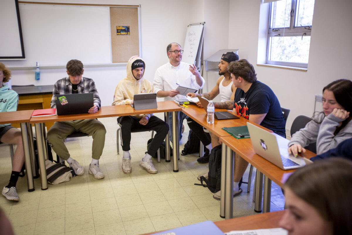 A male teacher telling his students the assignment. - Full Size