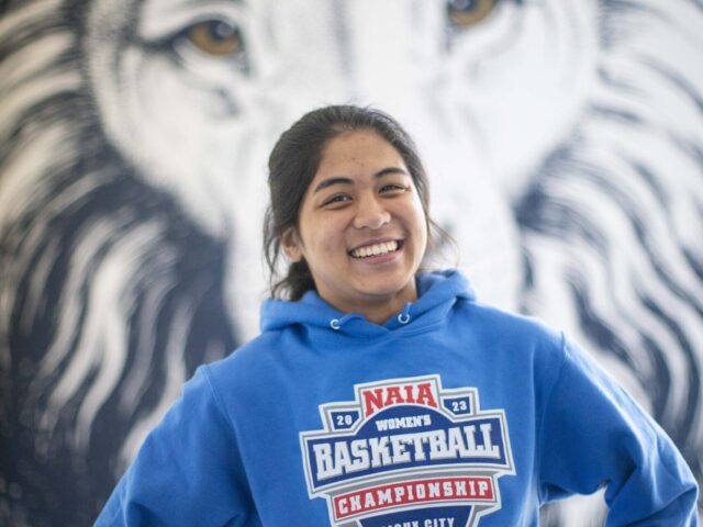 Nursing student Bea Atienza poses in the Lion's Den with a Lion mural behind her