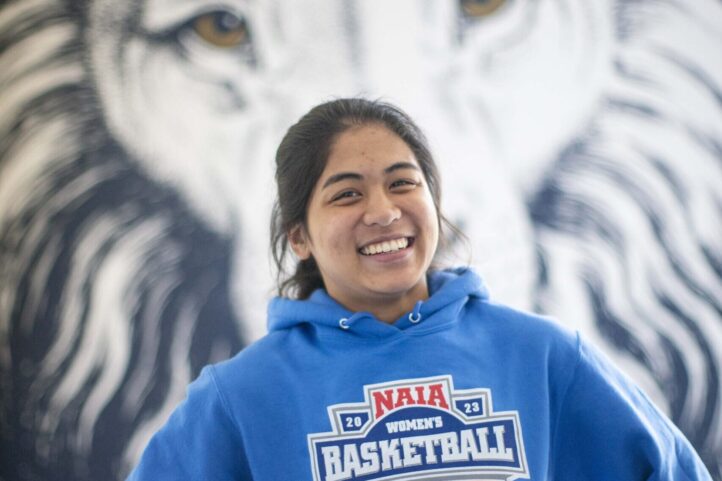 Nursing student Bea Atienza poses in the Lion's Den with a Lion mural behind her