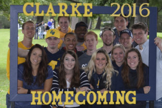 Clarke College students posing by Homecoming sign