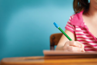 child-holding-pencil-at-desk