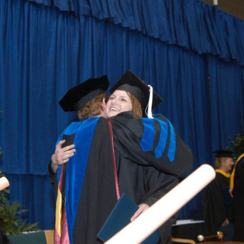 A graduate hugging her professor after receiving diploma.